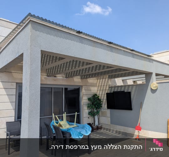 מרפסת עם שולחן וכיסאות, מטאטא ומסך טלוויזיה על הקיר